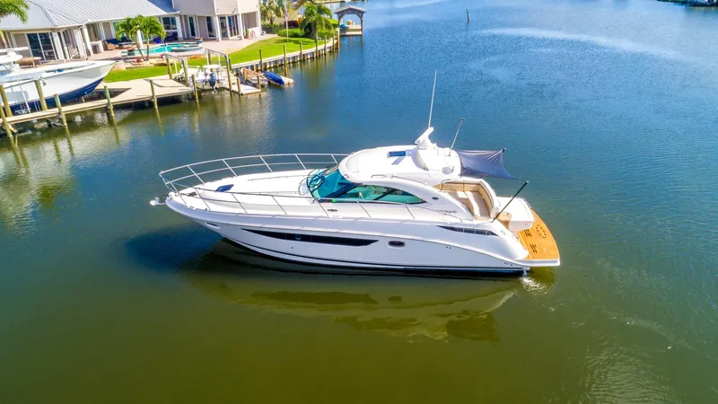 Slide: The Image of 2013 Sea Ray 410 Sundancer yacht on calm water near a dock. - 7