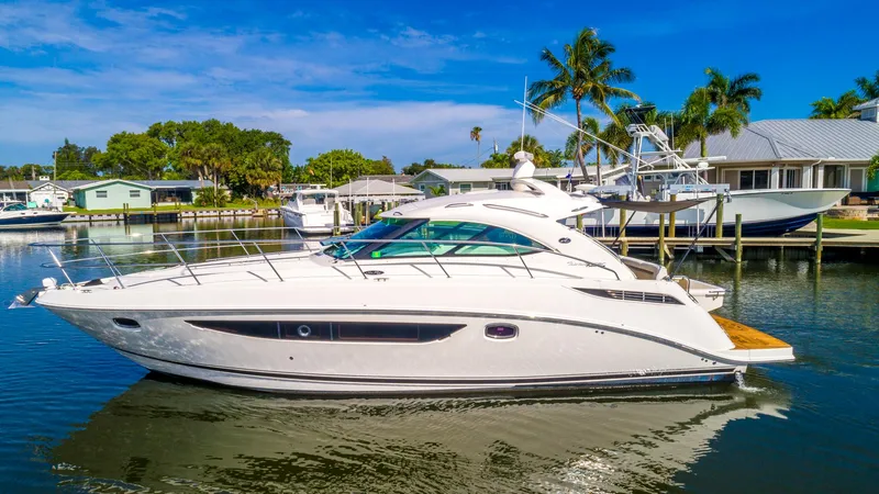 Slide: The Image of 2013 Sea Ray 410 Sundancer yacht docked in a sunny marina with palm trees. - 9