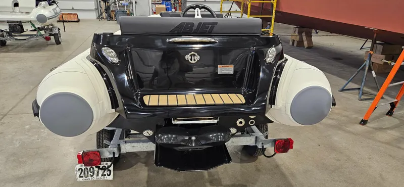 Slide: The Image of 2025 AB Inflatables 330 Jet Boat, rear view in a workshop setting. - 2