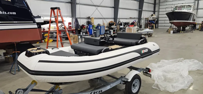 Slide: The Image of 2025 AB Inflatables 330 Jet Boat in a workshop on a trailer. - 3