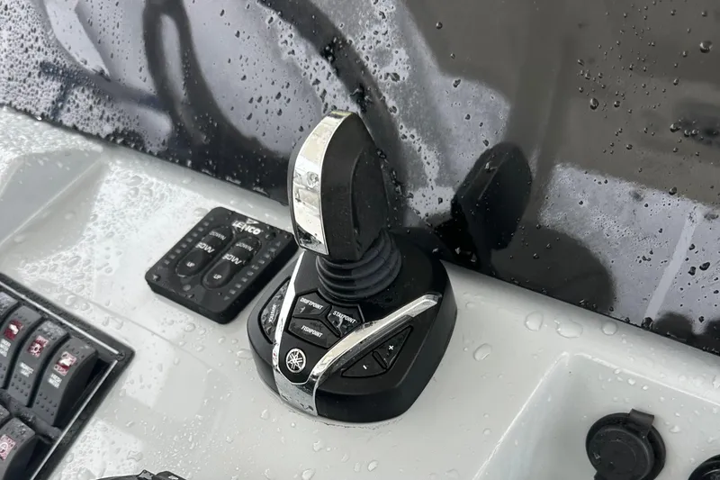 Slide: The Image of 2024 Pursuit S 328 Sport boat control panel with joystick and buttons, wet surface. - 10