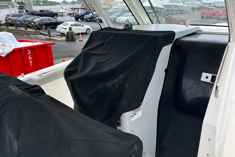 Slide: The Image of 2024 Pursuit S 328 Sport boat interior with covered seats, parked in a marina. - 11