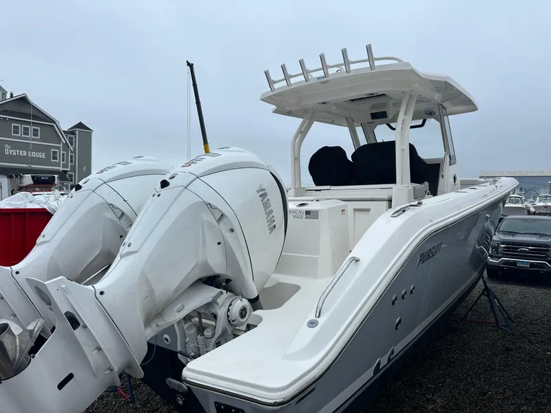 Slide: The Image of 2024 Pursuit S 328 Sport boat with dual engines, docked near a building. - 4