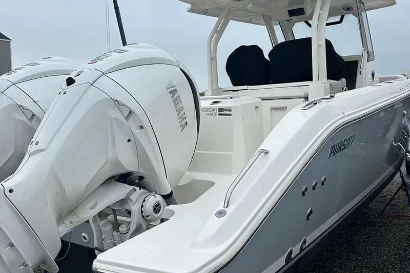 Slide: The Image of 2024 Pursuit S 328 Sport boat with dual Yamaha engines, docked on gravel. - 5