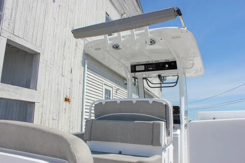 Slide: The Image of 2025 Sea Hunt Ultra 275 SE boat with T-top and seating, docked near a wooden building. - 10