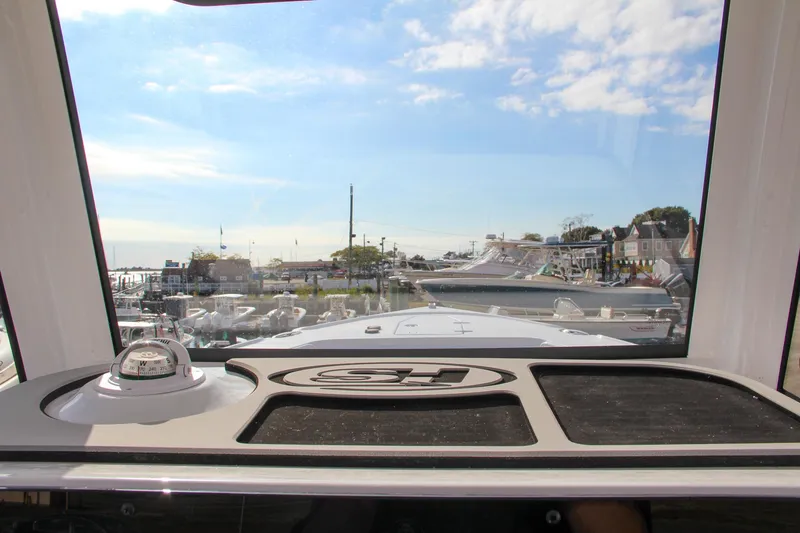 Slide: The Image of View from 2025 Sea Hunt Ultra 275 SE boat dashboard, overlooking marina and clear sky. - 40