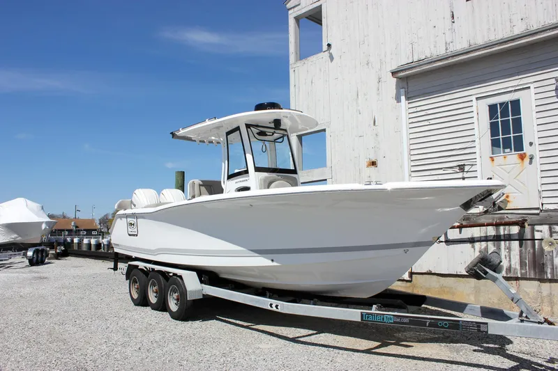 Slide: The Image of 2025 Sea Hunt Ultra 275 SE boat on a trailer, parked near a building. - 7