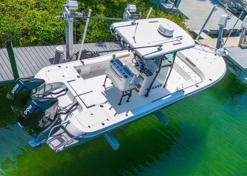 Slide: The Image of 2023 Caymas 28 HB boat docked in clear green water, featuring dual outboard engines. - 2