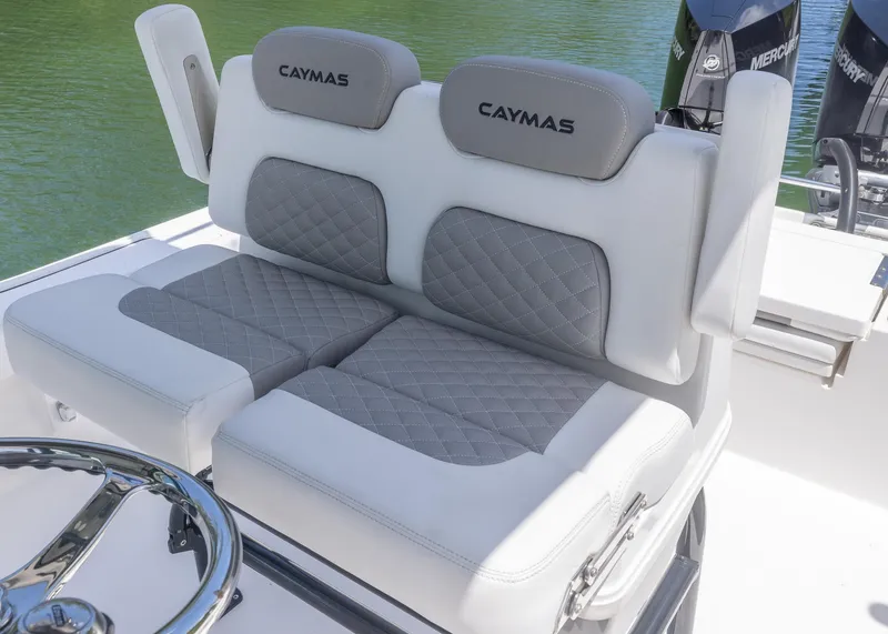 Slide: The Image of 2023 Caymas 28 HB boat with cushioned seating and steering wheel, on calm water. - 22