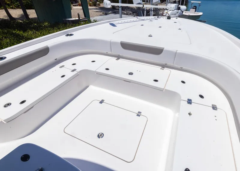 Slide: The Image of 2023 Caymas 28 HB boat deck with storage compartments, docked by clear blue water. - 7