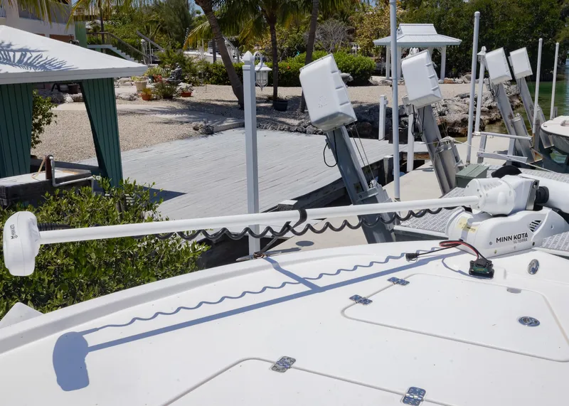 Slide: The Image of 2023 Caymas 28 HB boat with Minn Kota trolling motor, docked near a tropical setting. - 9