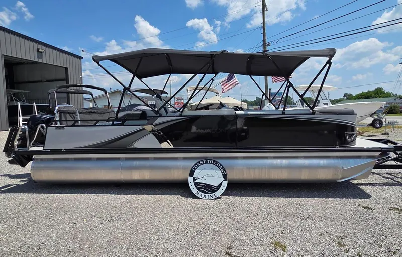 Slide: The Image of 2025 Avalon Platinum LSZ 2585 Versatile Rear Bench pontoon boat, parked outdoors under a clear sky. - 2