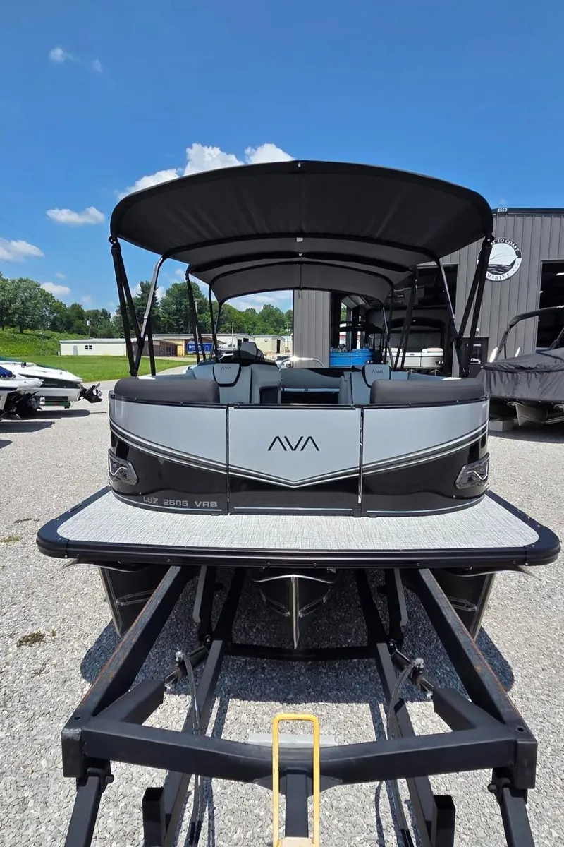 Slide: The Image of 2025 Avalon Platinum LSZ 2585 Versatile Rear Bench pontoon boat, parked outdoors under clear blue sky. - 3