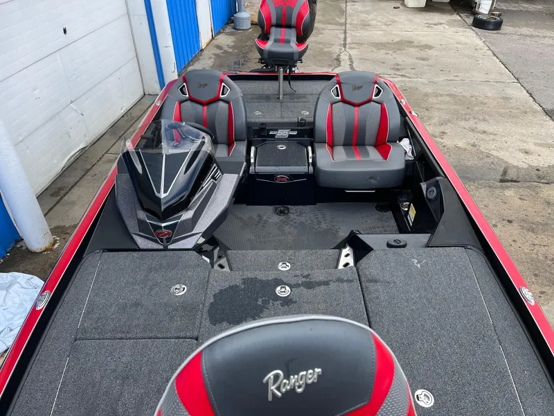 Slide: The Image of 2023 Ranger Z521R boat interior with red and gray seating, docked near a blue building. - 6