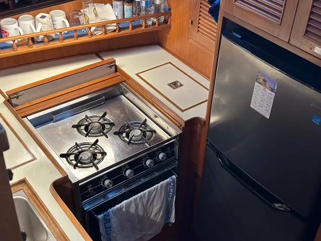 Slide: The Image of 1987 Albin Double Cabin kitchen with stove, fridge, and storage shelves. - 13