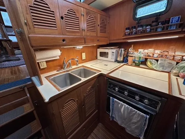 Slide: The Image of 1987 Albin Double Cabin kitchen with wooden cabinets, dual sink, stove, and microwave. - 14