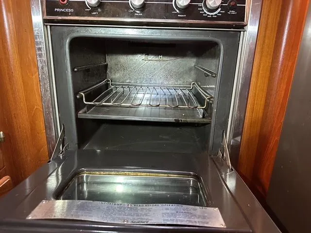 Slide: The Image of Open oven inside 1987 Albin Double Cabin boat, featuring metal rack and control knobs. - 15