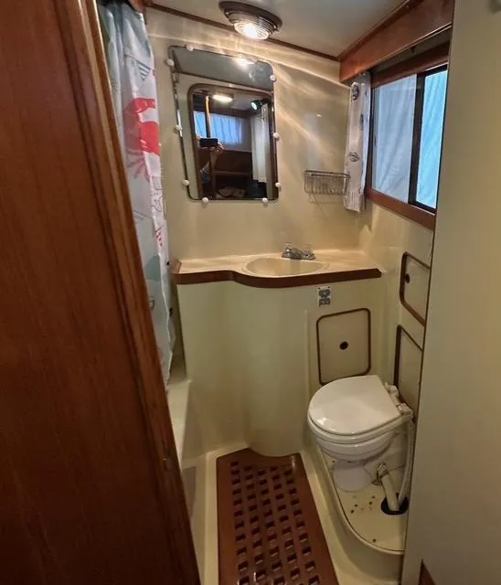 Slide: The Image of 1987 Albin Double Cabin bathroom with sink, toilet, mirror, and shower curtain. - 20