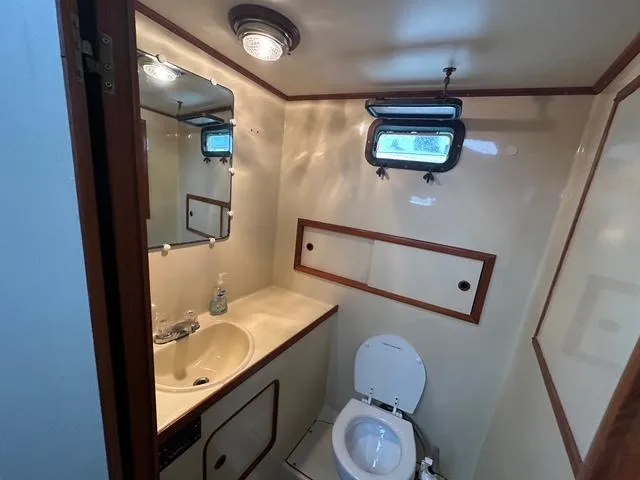 Slide: The Image of 1987 Albin Double Cabin bathroom with sink, toilet, mirror, and porthole window. - 27
