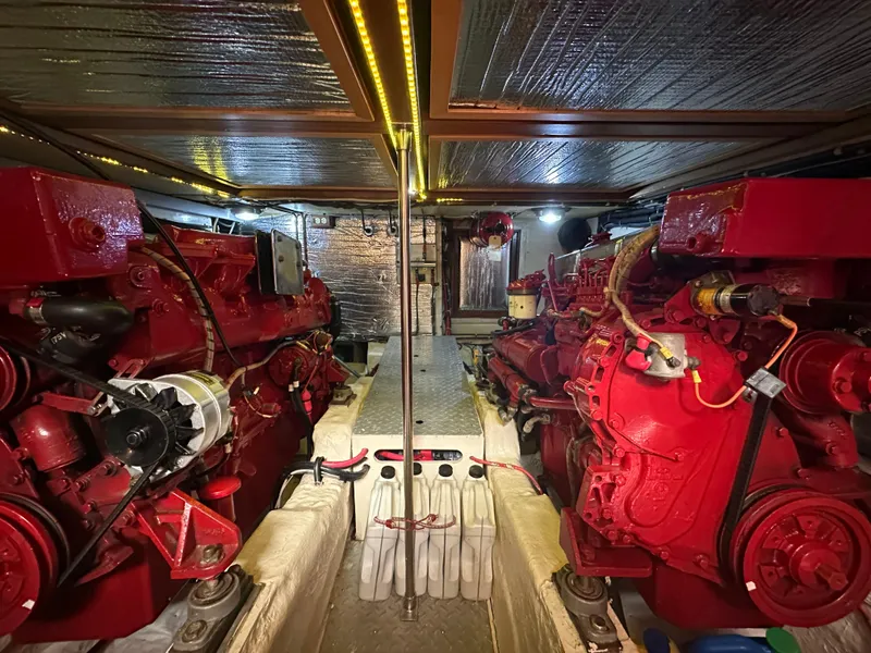 Slide: The Image of Engine room of a 1987 Albin Double Cabin boat with red engines and metallic ceiling. - 31