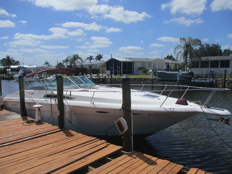 The Image of 1991 Sea Ray 350 Express Cruiser docked by wooden pier under blue sky. - 1