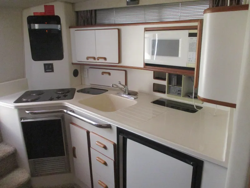 Slide: The Image of 1991 Sea Ray 350 Express Cruiser kitchen with stove, sink, microwave, and storage cabinets. - 17