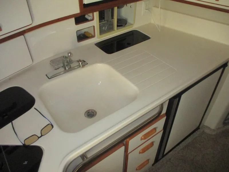 Slide: The Image of 1991 Sea Ray 350 Express Cruiser kitchen with sink, stove, and storage cabinets. - 22