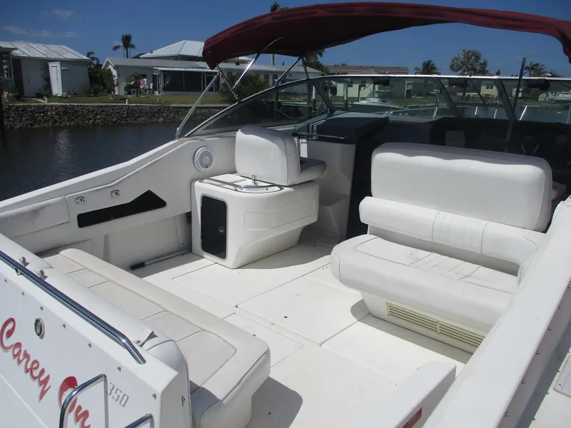 Slide: The Image of 1991 Sea Ray 350 Express Cruiser with white seating and red canopy, docked near waterfront homes. - 3