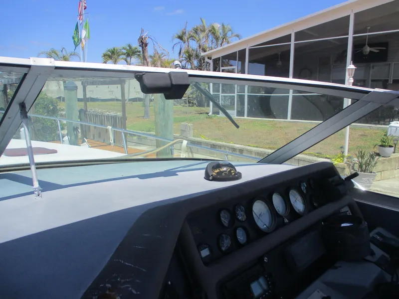Slide: The Image of 1991 Sea Ray 350 Express Cruiser dashboard with gauges, docked near a residential area. - 39
