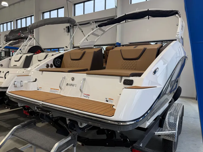 Slide: The Image of 2025 Yamaha Boats 222SD, sleek design, brown seating, displayed indoors on a trailer. - 0