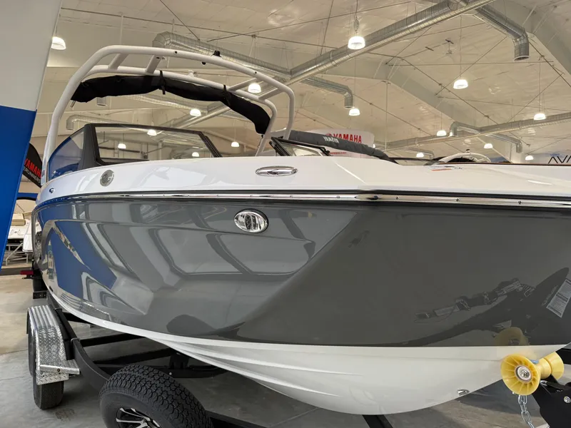 Slide: The Image of 2025 Yamaha Boats 222SD in showroom, sleek design, gray and white exterior, on trailer. - 3