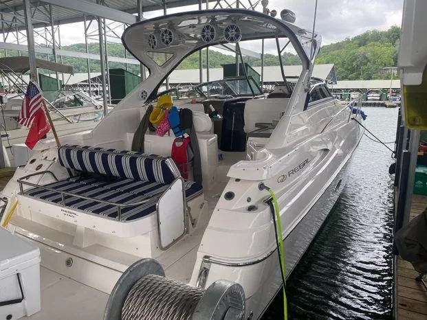 The Image of 2006 Regal Commodore 3760 IO boat docked, featuring striped seating and American flag. - 1