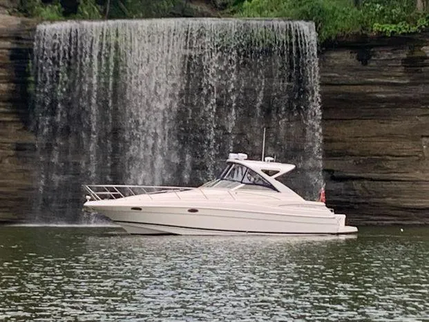 Slide: The Image of 2006 Regal Commodore 3760 IO boat cruising near a scenic waterfall. - 21