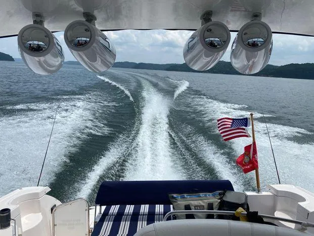 Slide: The Image of 2006 Regal Commodore 3760 IO cruising on a lake, American flag waving, scenic view. - 26