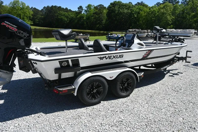 Slide: The Image of 2025 Vexus AVX 1980 boat on trailer, parked on gravel, surrounded by greenery. - 2