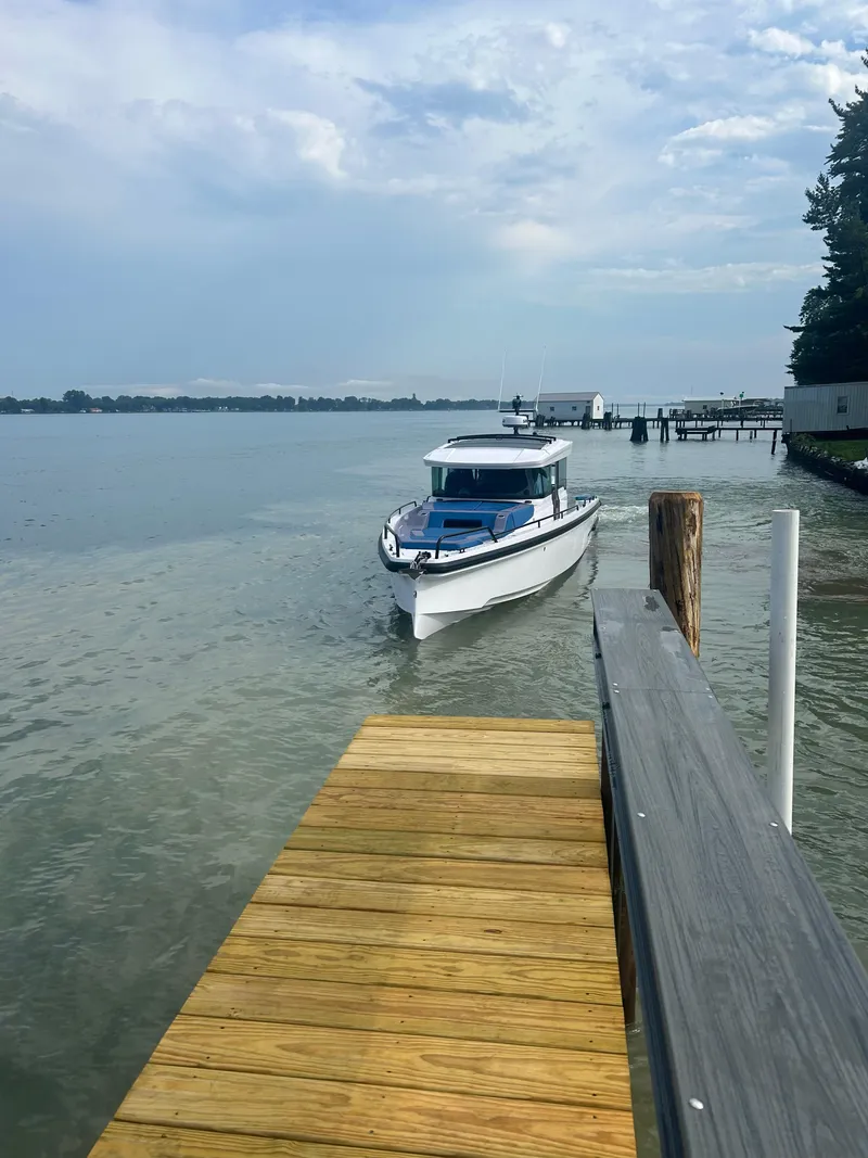 Slide: The Image of 2024 Axopar 37 XC Cross Cabin approaching dock on a calm lake. - 3