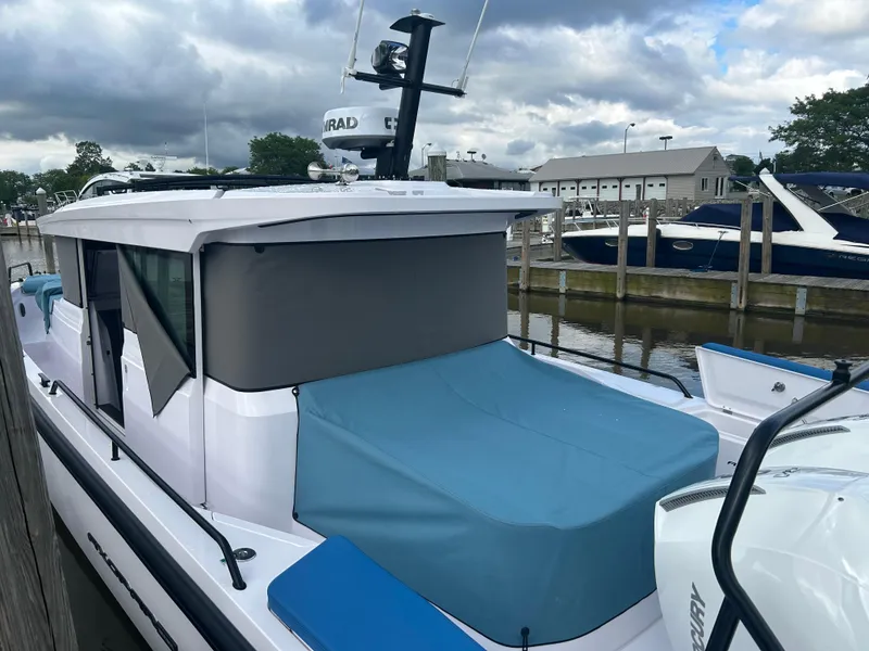 Slide: The Image of 2024 Axopar 37 XC Cross Cabin Aft Cabin docked, featuring sleek design and blue cover. - 5