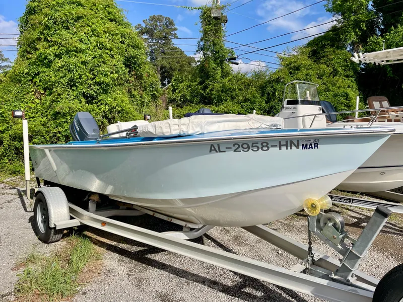 Slide: The Image of 1979 Negus 17 boat on trailer, parked outdoors, surrounded by greenery and other boats. - 1