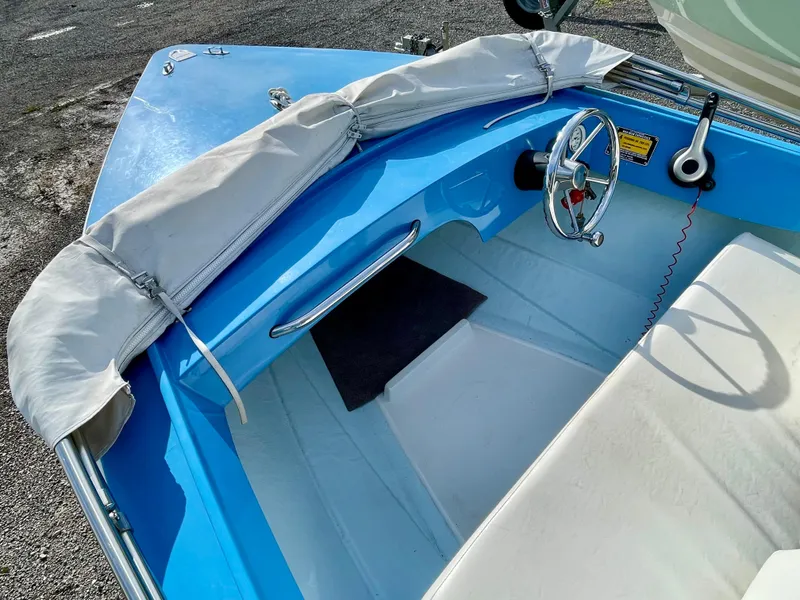 Slide: The Image of 1979 Negus 17 boat interior with blue and white design, steering wheel, and protective cover. - 8