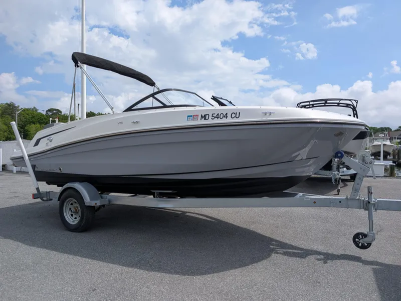 Slide: The Image of 2023 Bayliner VR5 Bowrider I/O on trailer, parked outdoors under a partly cloudy sky. - 2