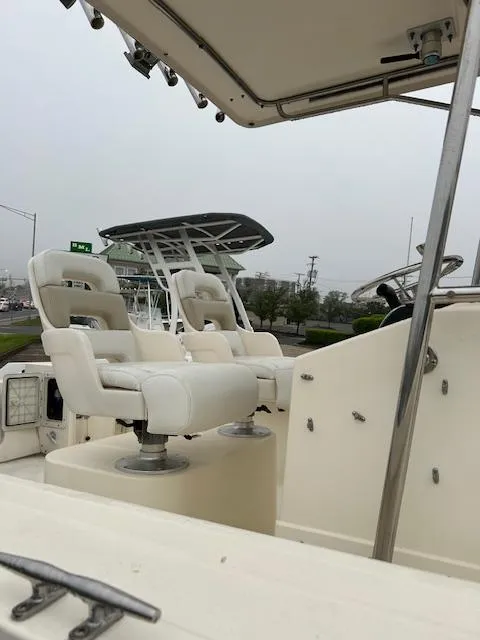 Slide: The Image of 1996 Parker 2300 DV Center Console boat with white seating and console, docked outdoors. - 3
