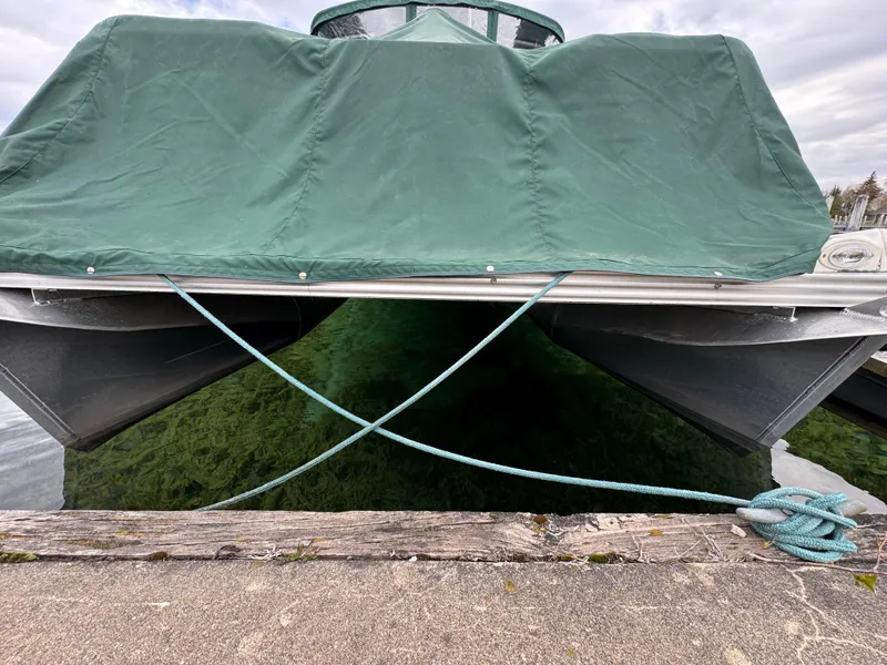 Slide: The Image of 2007 Manitou Legacy boat with green cover docked at a pier. - 14