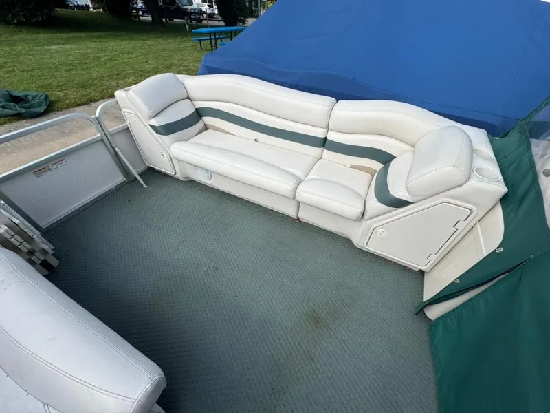 Slide: The Image of 2007 Manitou Legacy boat interior with white seating and green accents. - 2