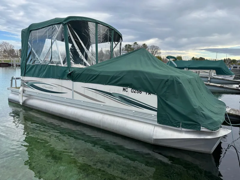 Slide: The Image of 2007 Manitou Legacy pontoon boat with green canopy docked on calm water. - 6