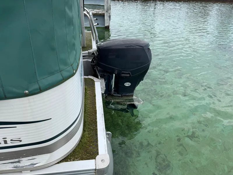 Slide: The Image of 2007 Manitou Legacy boat with outboard motor in clear water. - 9