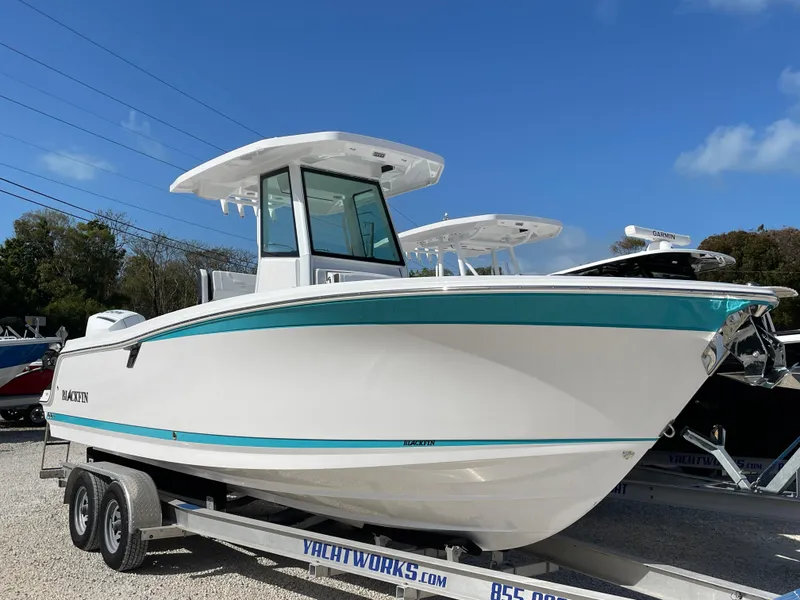 Slide: The Image of 2025 Blackfin 252CC boat on trailer, white with teal accents, under clear blue sky. - 37