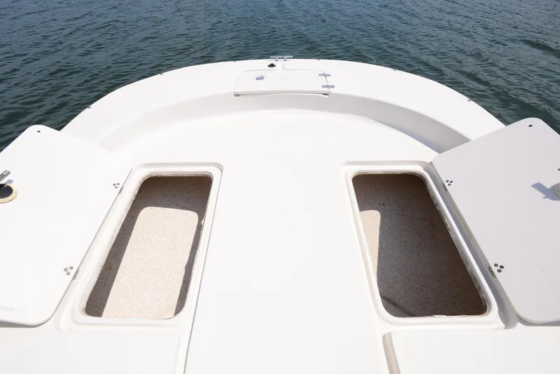 Slide: The Image of 2018 Carolina Skiff 218 DLV boat deck with open storage compartments on calm water. - 11