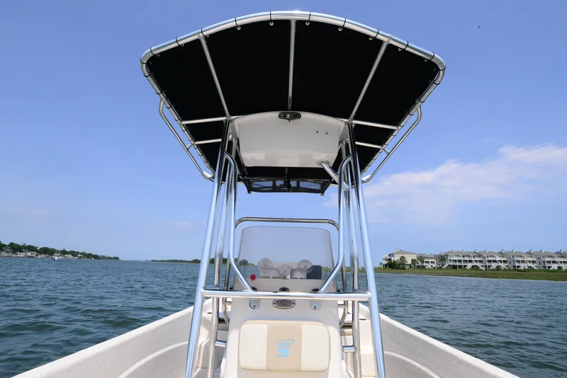 Slide: The Image of 2018 Carolina Skiff 218 DLV boat on water, featuring T-top and console. - 13