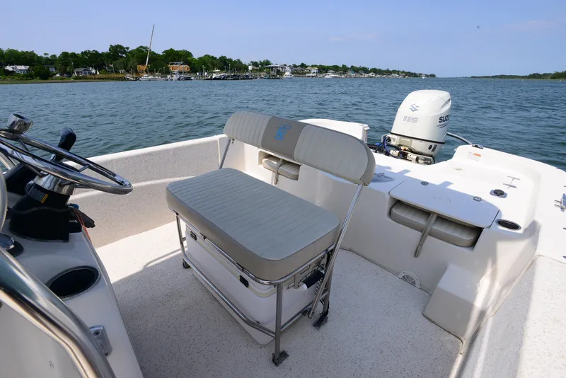 Slide: The Image of 2018 Carolina Skiff 218 DLV boat interior with seating and steering, overlooking a scenic waterway. - 15