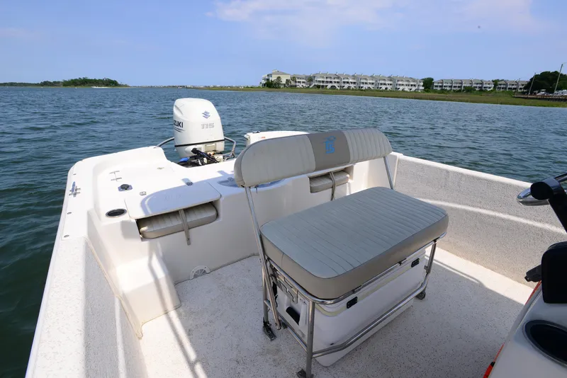 Slide: The Image of 2018 Carolina Skiff 218 DLV boat on water, featuring seating and outboard motor. - 16
